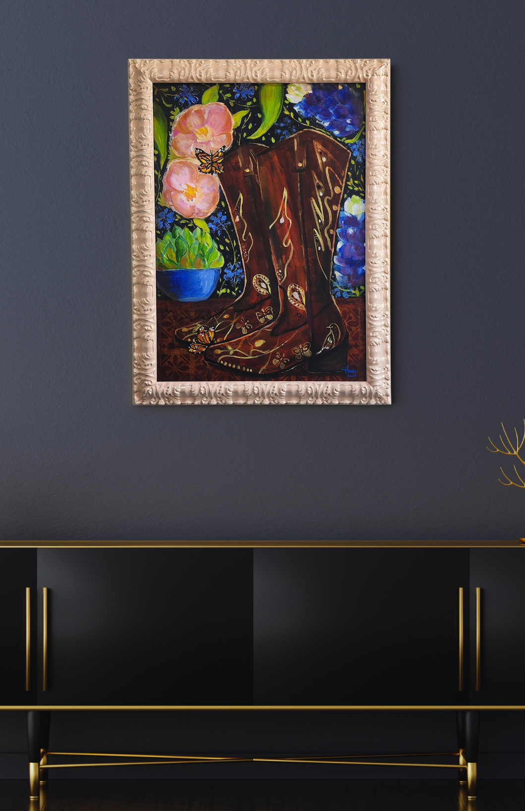 Framed artwork of a boot with flowers on a dark wall above a black console table.