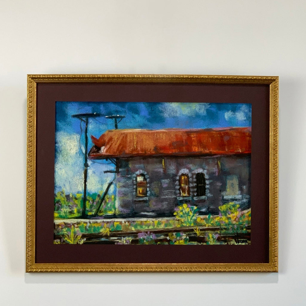 Framed painting of a rustic building with a rusted roof on a white wall