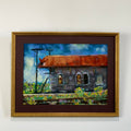 Framed painting of a rustic building with a rusted roof on a white wall